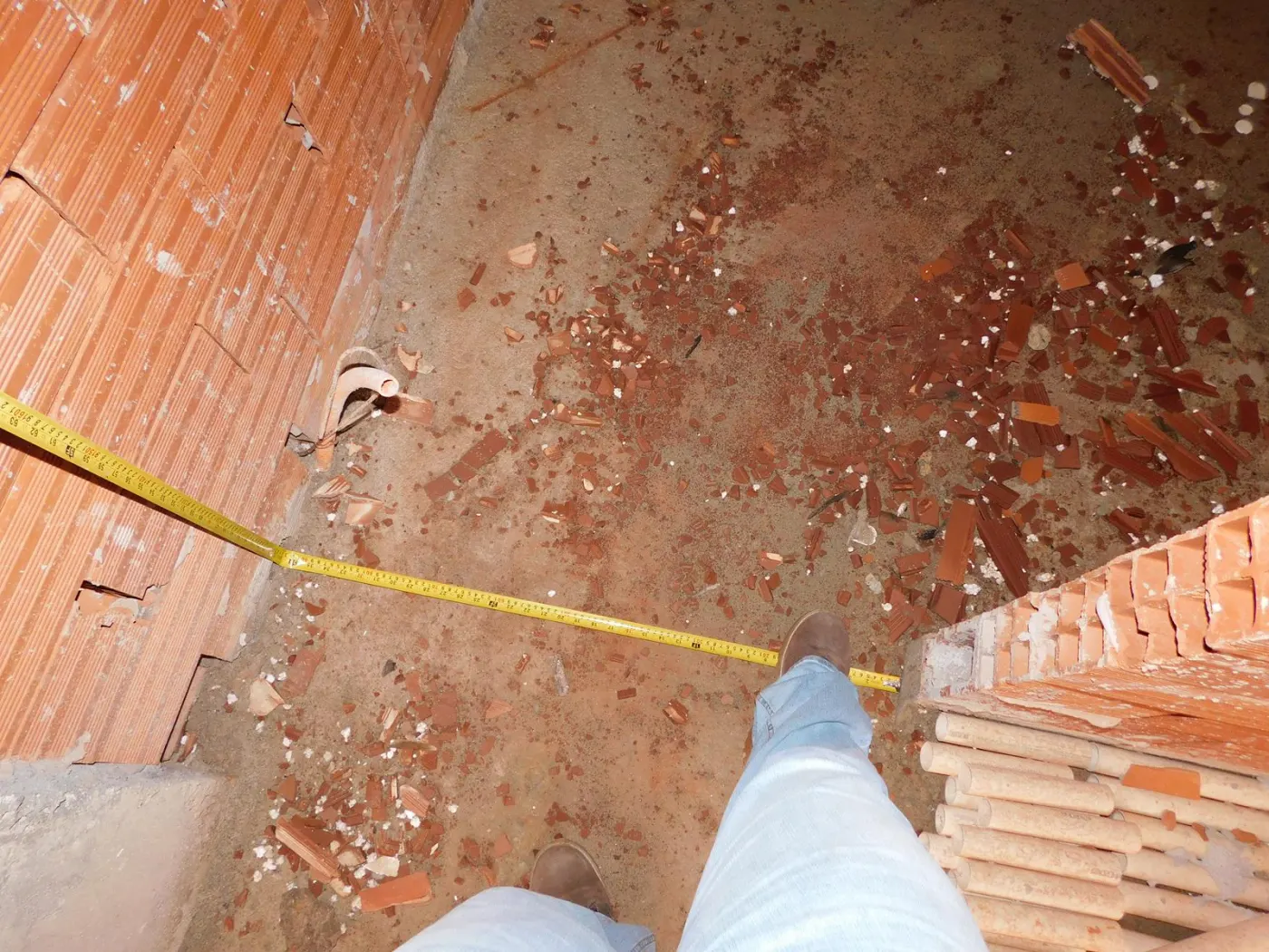 Trena estendida no piso de uma obra entre duas paredes de tijolo